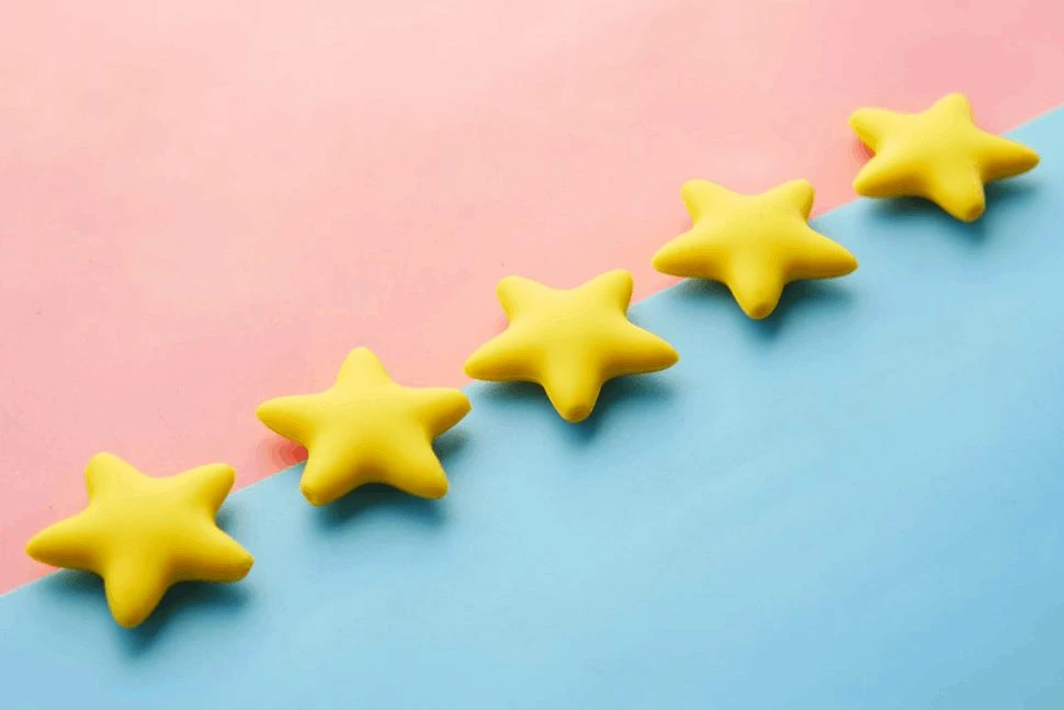 5 golden stars made of play dough in front of a pink and blue background.