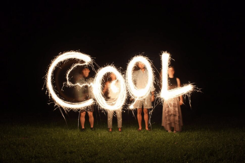 Four people holding up fireworks and forming the word cool.