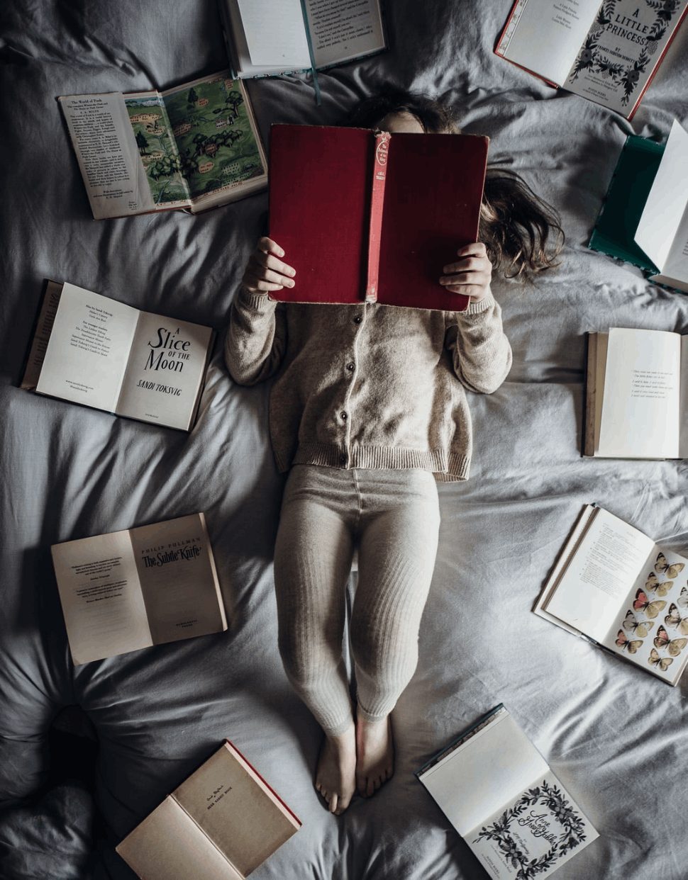 Someone reading many books on their bed to practice speed reading.