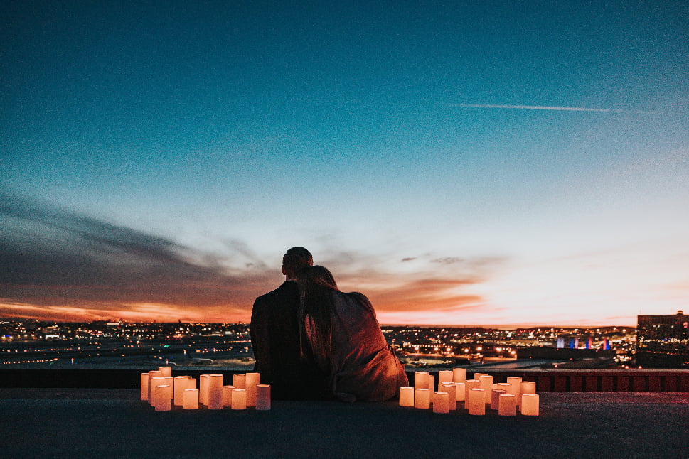 A couple sitting and watching the sunset over the city.