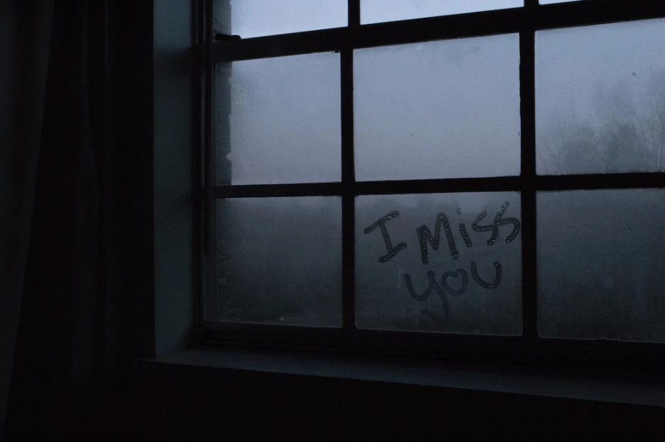 I Miss You text written on a glass window.