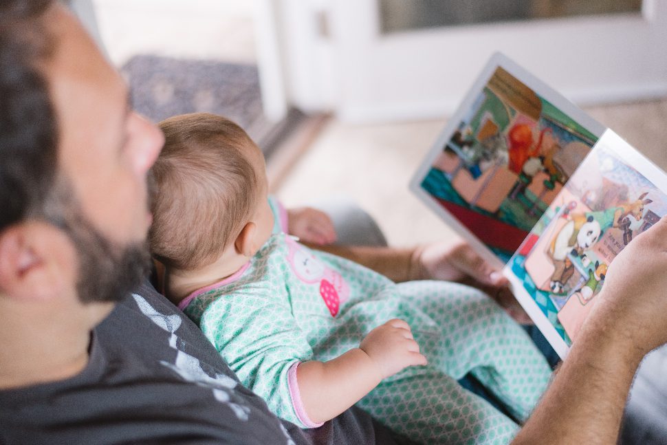 Dad and baby reading so that developing reading skills later for the child is easier.