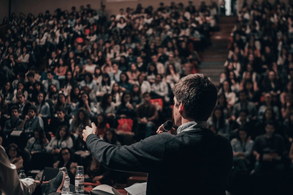 man giving a speech in front of a crowd.