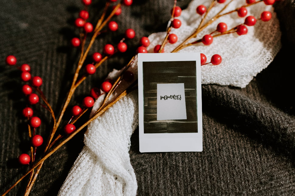 A polaroid photo with the word Memories placed next to a white scarf.