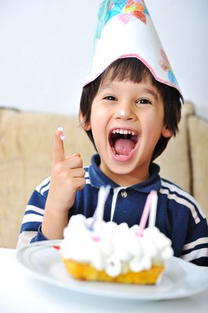 birthday boy seated in front of cake and smiling broadly