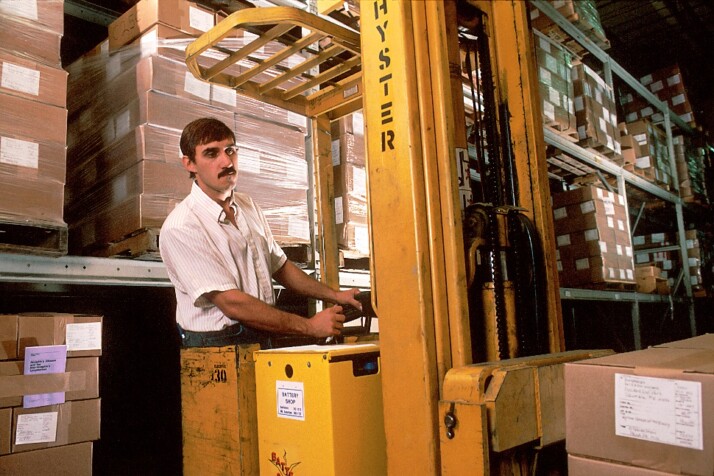 A man operating a forklift to move boxes around the warehouse.