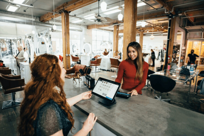 two women near tables talking to each other and smiling