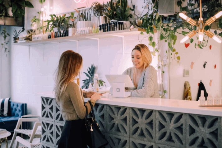 two woman facing on white counter and smiling at each other