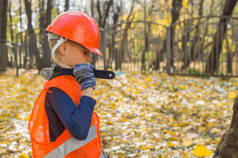 boy in orange and black jacket wearing red helmet holding black dslr camera