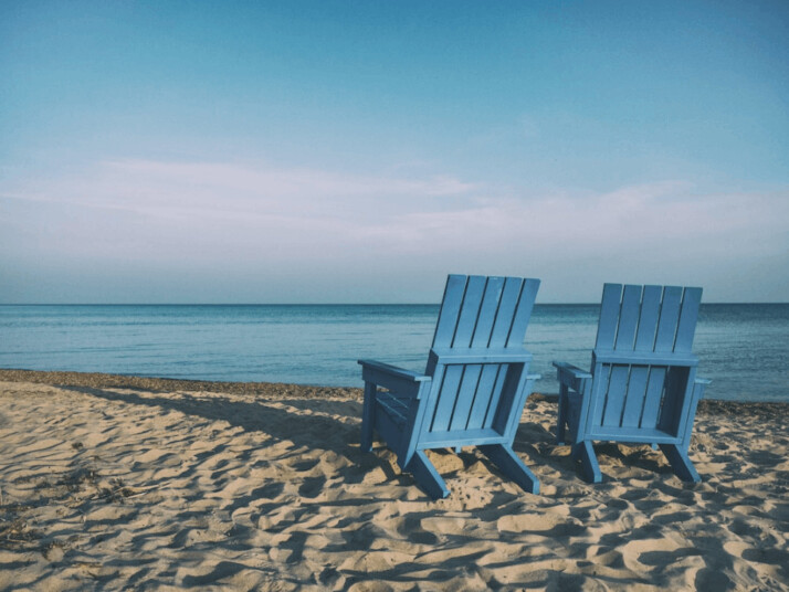 two blue beach chairs near body of water