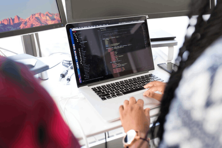 a woman using a MacBook Pro laptop and coding