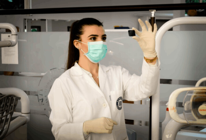 a woman in a white apron inside a laboratory checking the readings