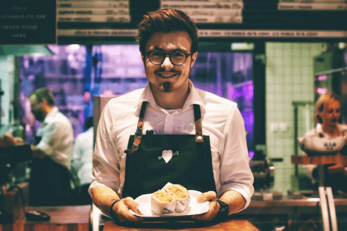 a food server holding a fish dish on plate and smiling