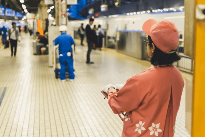 back of woman wearing fitted cap standing in train station