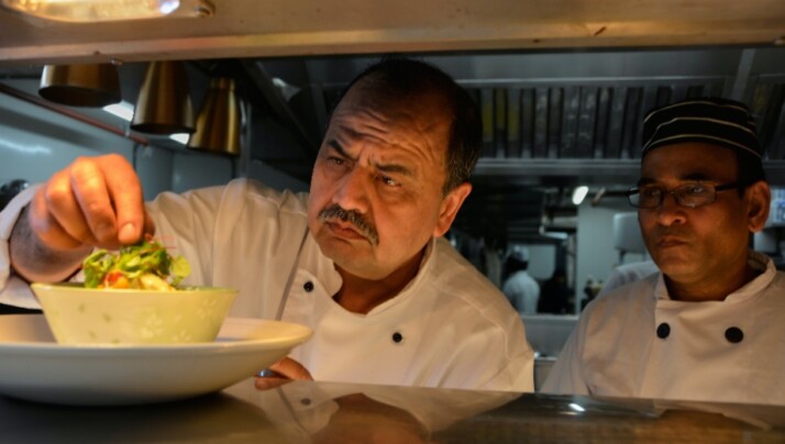 The head cook plating one of his dishes in a bowl.