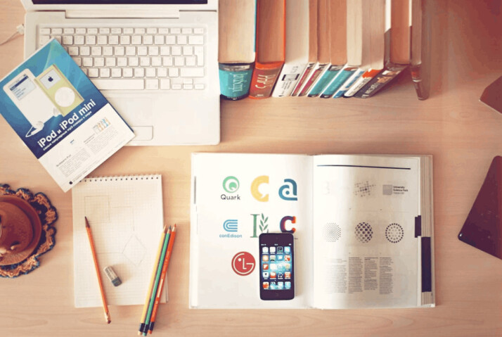 pencils, a laptop, smartphone, and books on top of a wooden table