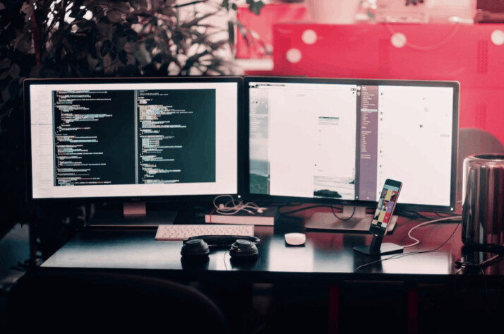 two black computer monitors on black table