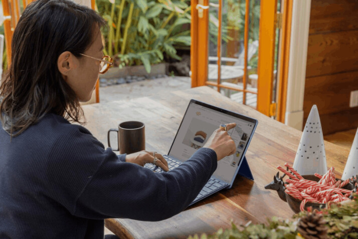 a lady using a laptop and pointing a finger on the screen