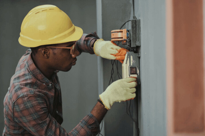 An electrical technician wearing a work helmet and working with a circuit