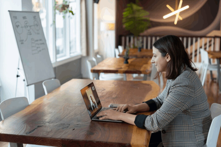 woman in gray and white striped long sleeve shirt using silver macbook