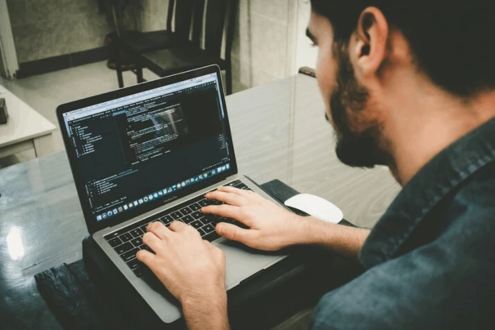 a software engineer programming using his MacBook Pro laptop.