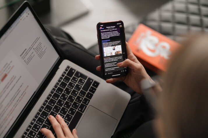 A person using their laptop and phone at the same time.