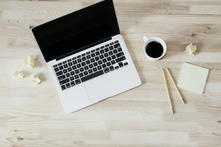 Turned off MacBook Pro beside white ceramic mug filled with coffee