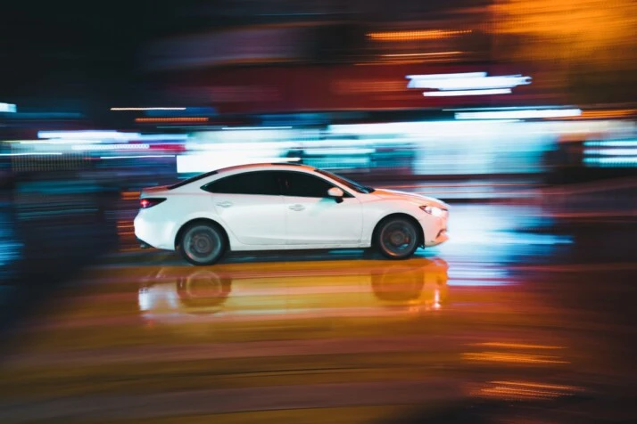 A white car speeding through a road.