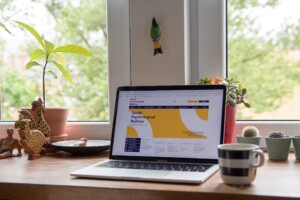 A laptop displaying a Social Psychological Bulletin website placed on a neat wooden table.