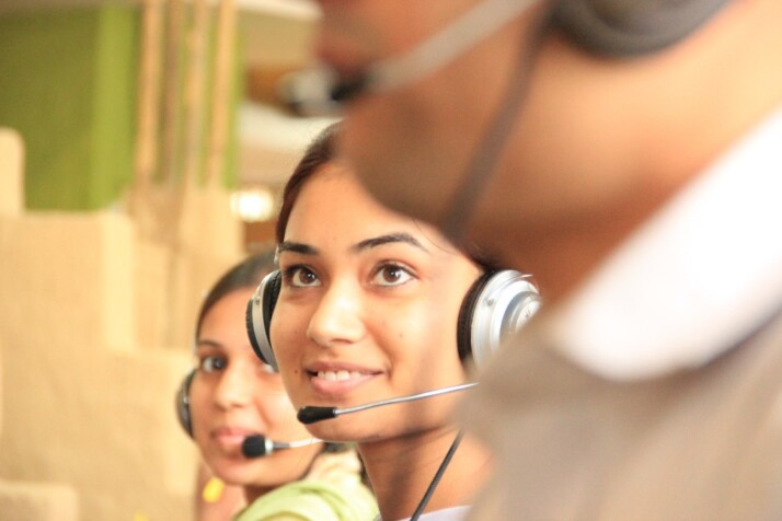A customer service representative smiling and wearing her headset.