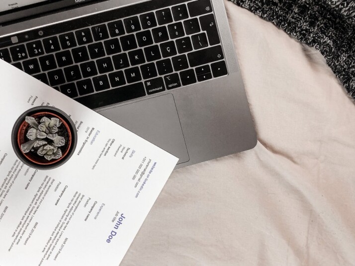 A printed resume placed on top of a laptop.