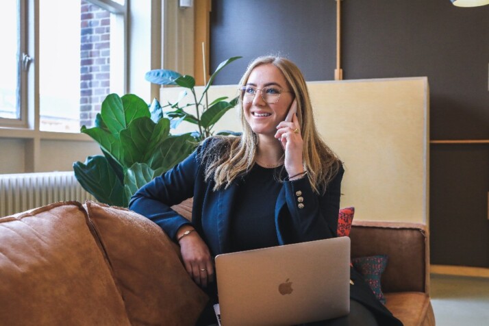 A woman with a MacBook Pro laptop on her lap and talking on the phone