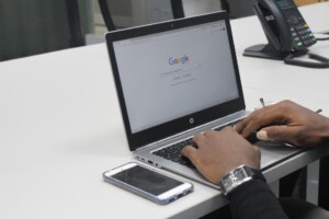 A person entering a search term on the Google Homepage using his laptop.