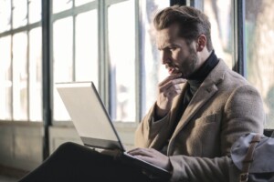 A man thinking about something while working on his laptop.