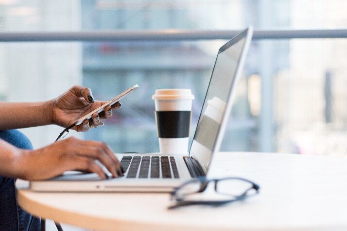 A person working on their laptop while using their phone.