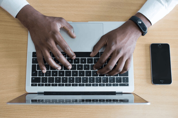 person's hand on MacBook near iPhone flat lay photography