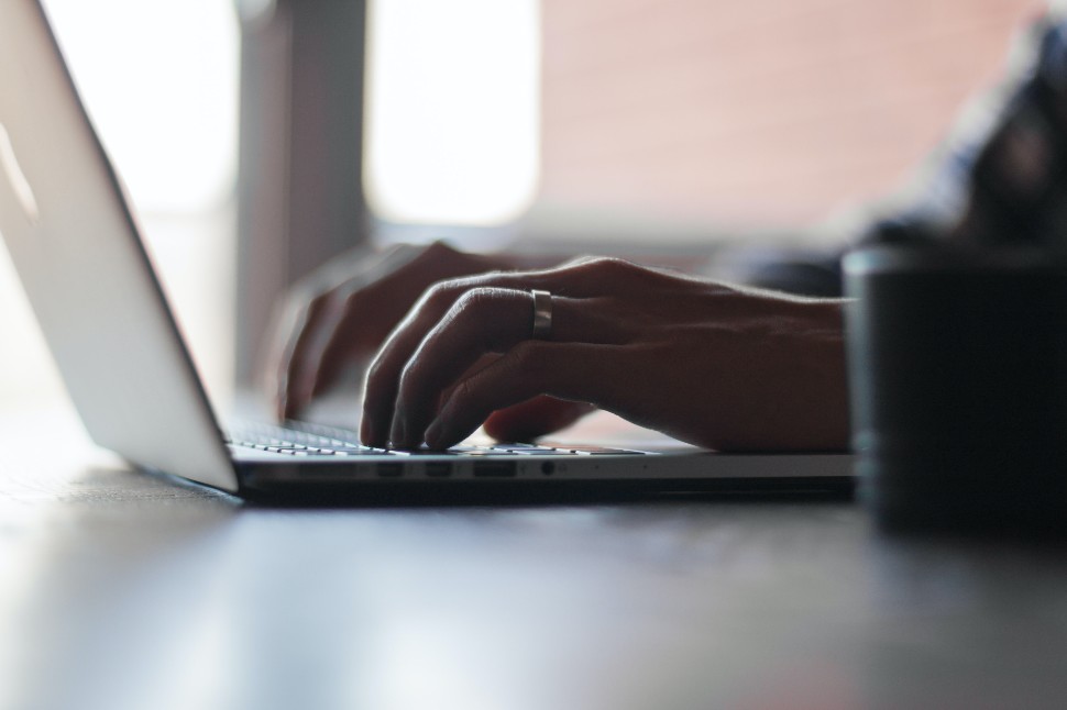 Someone wearing a ring typing something on their laptop.