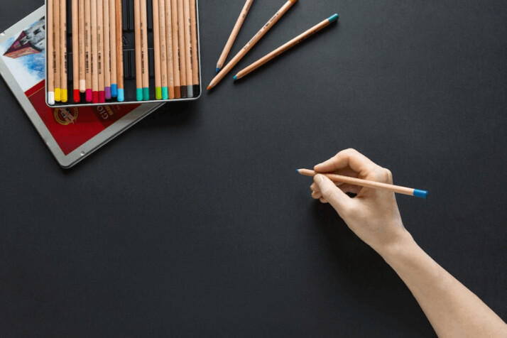 person holding brown pencil near pack of brown pencils  