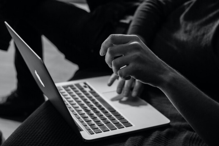 A black and white photo of a person working on a laptop