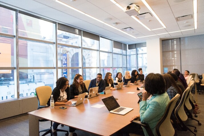 A large team having a meeting while seated across a long office table.