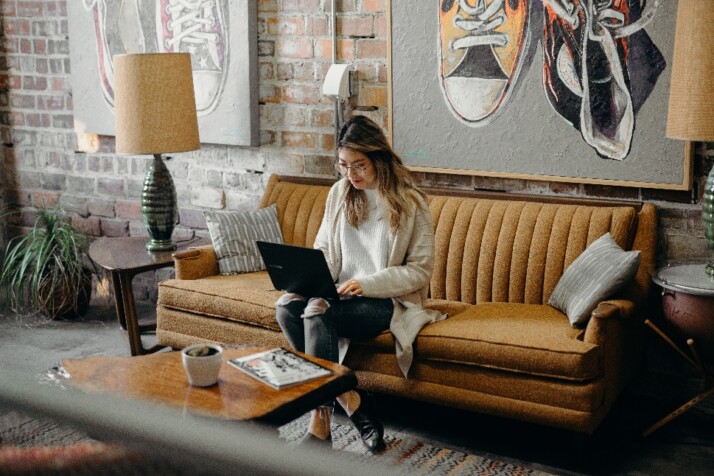 A woman sitting on a couch while working on her laptop.