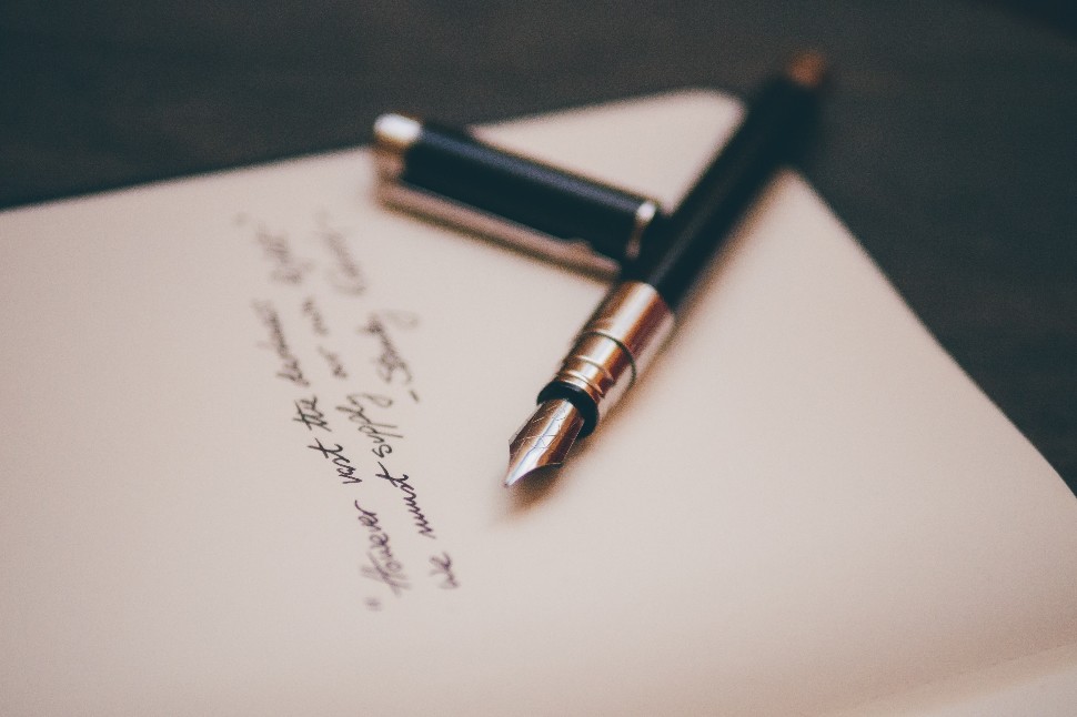 Classic quill pen and hand-written message on notebook paper for an antique touch.