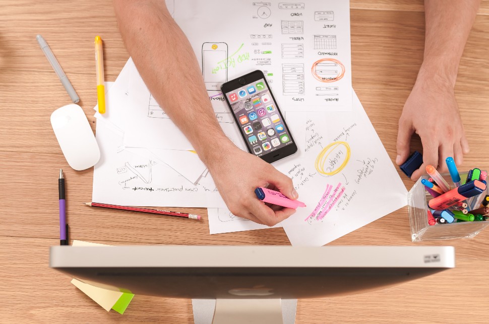Focused worker marking papers while checking phone for updates.