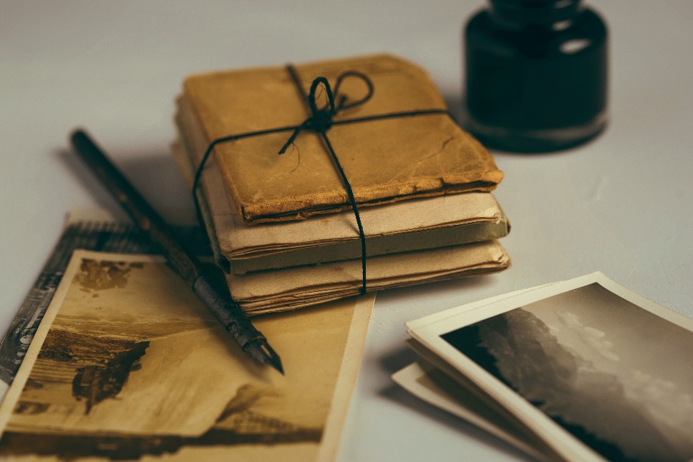 Quill pen surrounded by vintage photographs and historical documents.