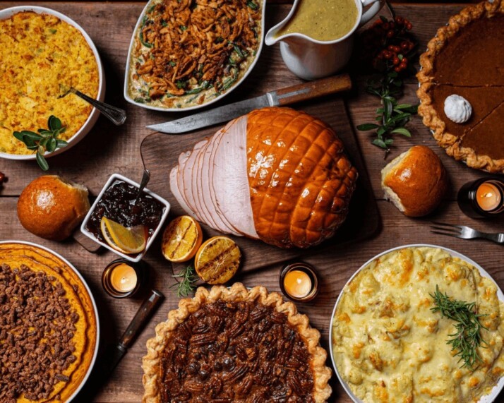 Thanksgiving table prepared on a wooden table with a variety of dishes.